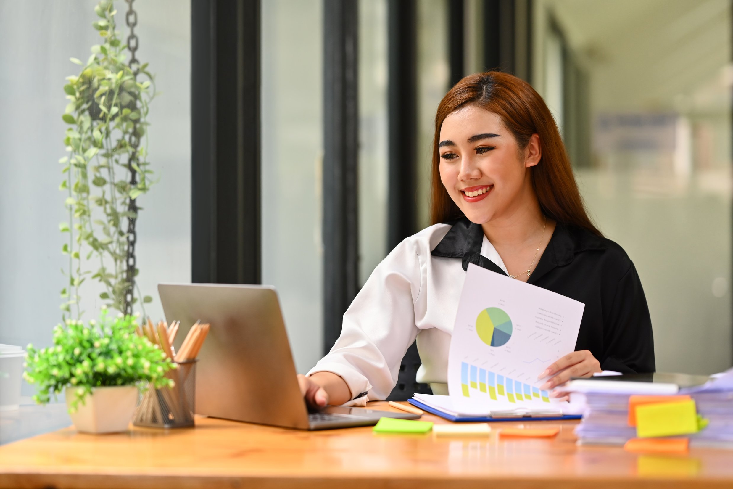 Image of cheerful asian female office worker reading email, usin